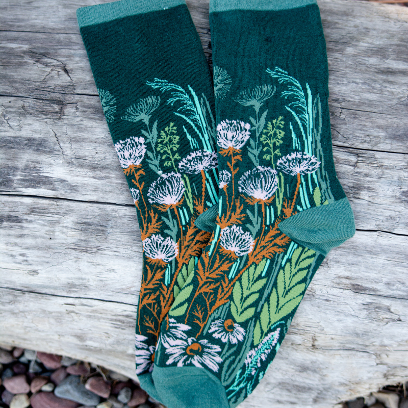 Pair of green socks with floral pattern on a wooden surface
