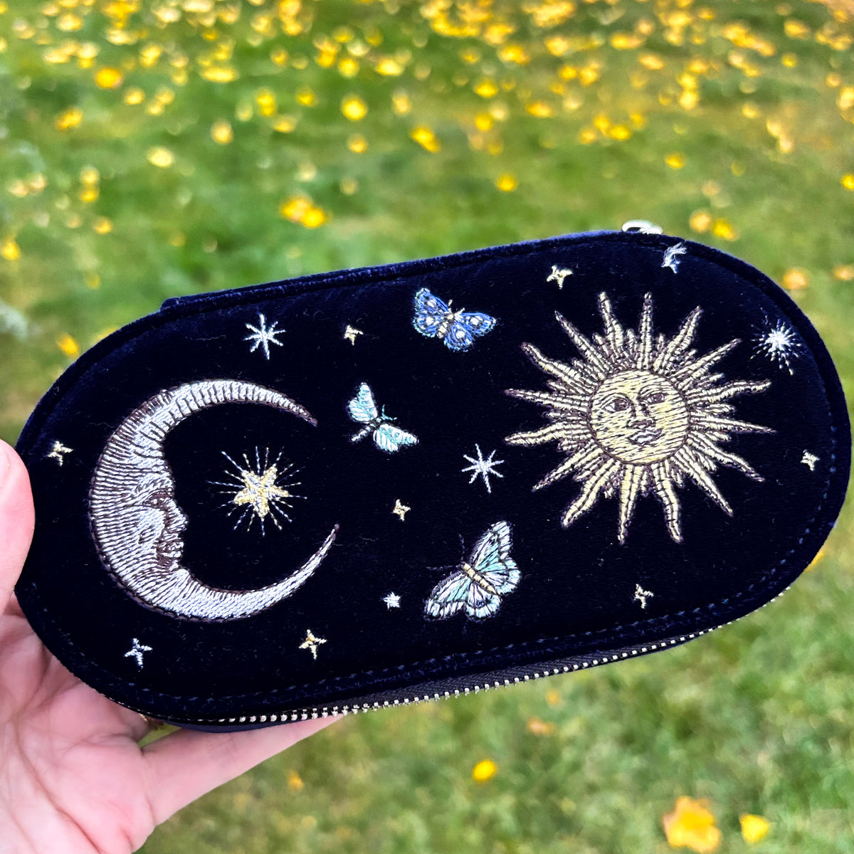 Navy blue velvet travel jewelry case embroidered with a gold sun, silver crescent moon, stars, and butterflies