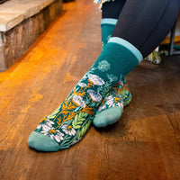 Teal socks with floral pattern worn on a wooden floor