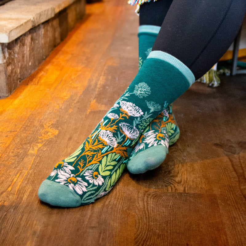 Teal socks with floral pattern worn on a wooden floor