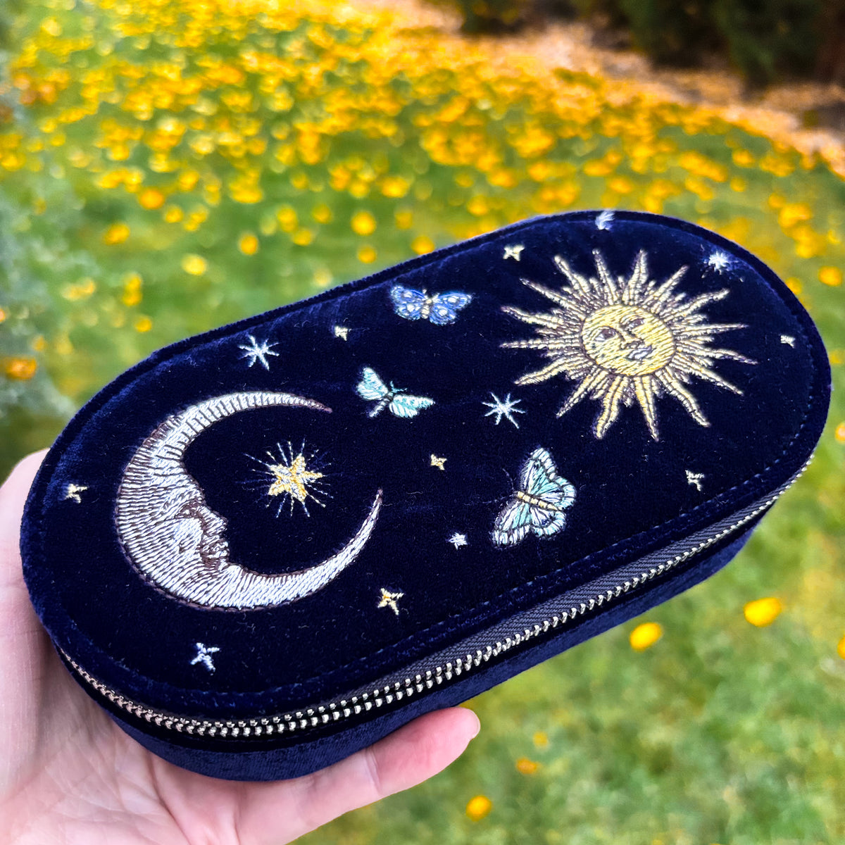 Navy blue velvet travel jewelry case embroidered with a gold sun, silver crescent moon, stars, and butterflies
