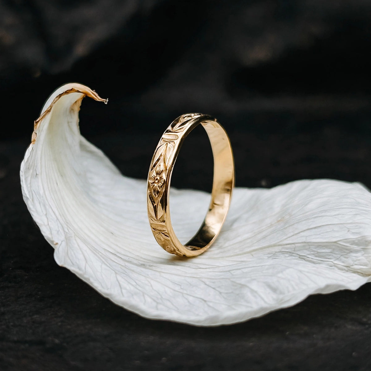 Art Deco stacking ring in solid 14k gold standing on a white flower petal
