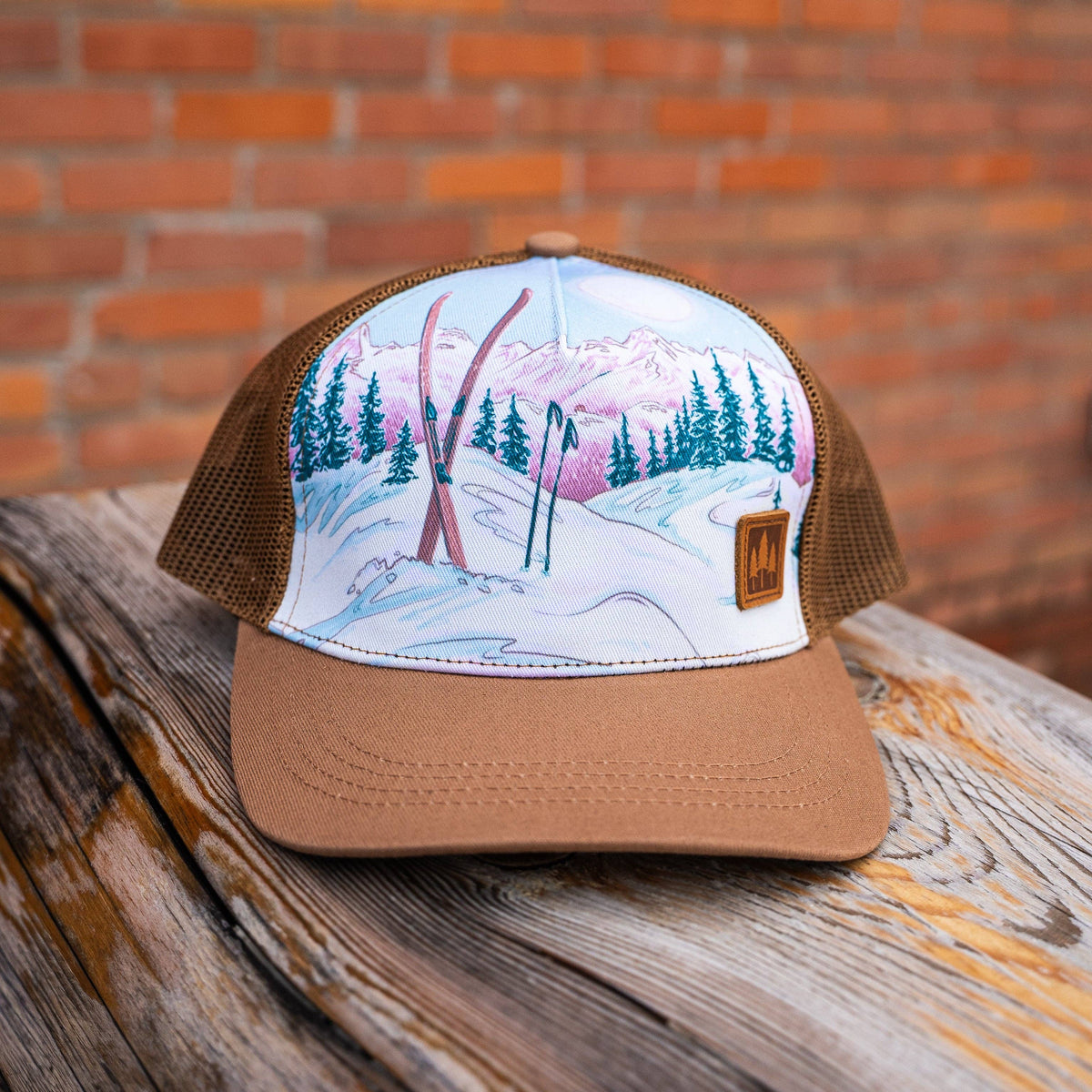 Trucker hat with a winter landscape design on a wooden surface with a brick background