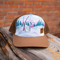 Trucker hat with a winter landscape design on a wooden surface with a brick background