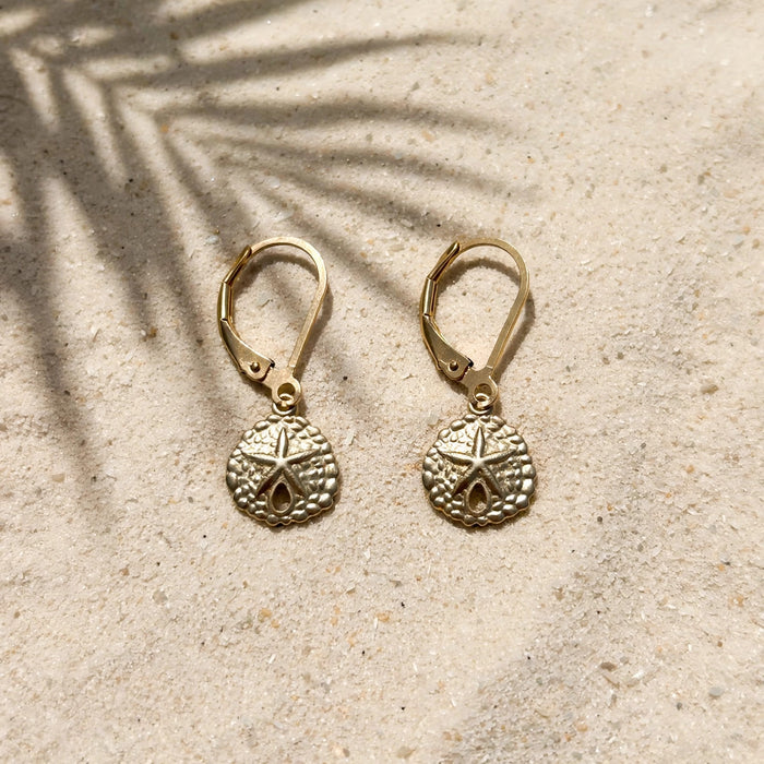Beachcombers Small Sand Dollar Earrings in 14k gold fill, styled on pale sand at the beach
