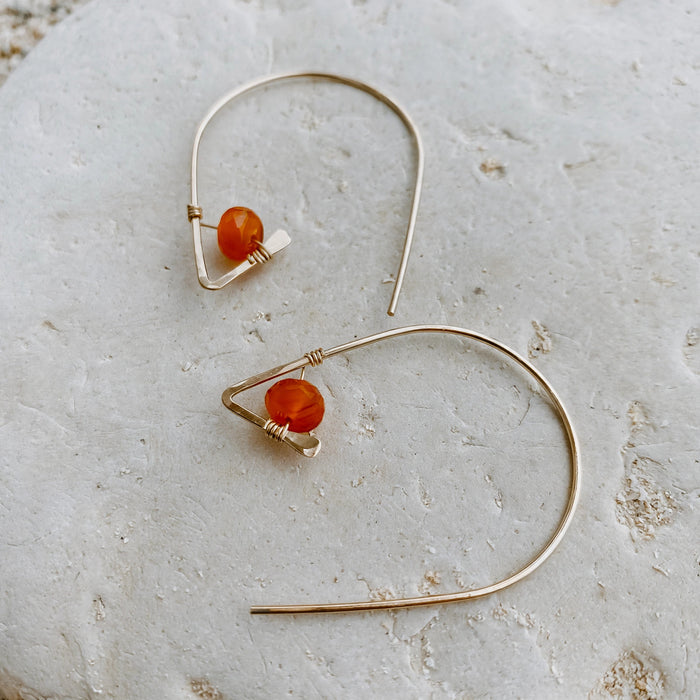 Carnelian Ear Threaders in 14k gold fill, styled on pale sand at the beach