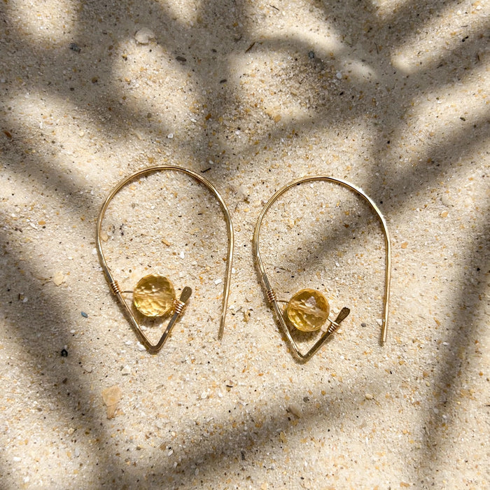 Citrine Ear Threaders in 14k gold fill, styled on pale sand at the beach