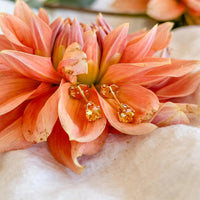 Citrine stud earrings in solid 14k gold nestled in a coral dahlia bloom
