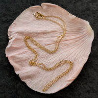 Dainty chain necklace in solid 14k gold looped on a single blush petal