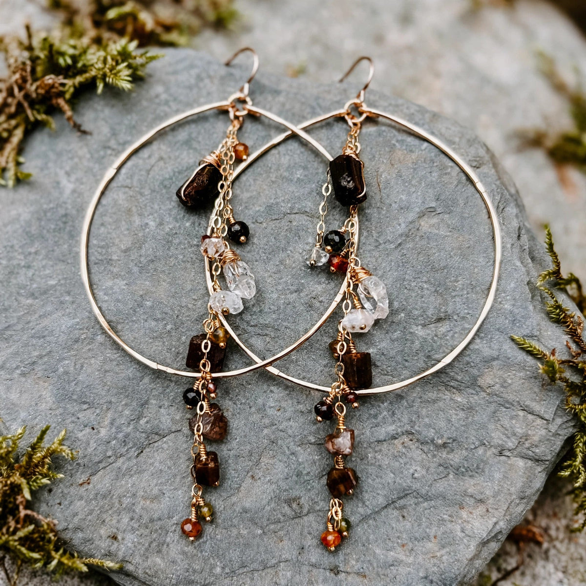 Enchanted Earth Hoop Earrings in 14k gold fill with hammered hoops, resting on a gray stone