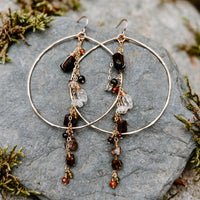Enchanted Earth Hoop Earrings in 14k gold fill with hammered hoops, resting on a gray stone
