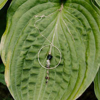 Enchanted Earth Hoop Necklace in 14k gold fill with a hammered hoop pendant, resting on a large green leaf