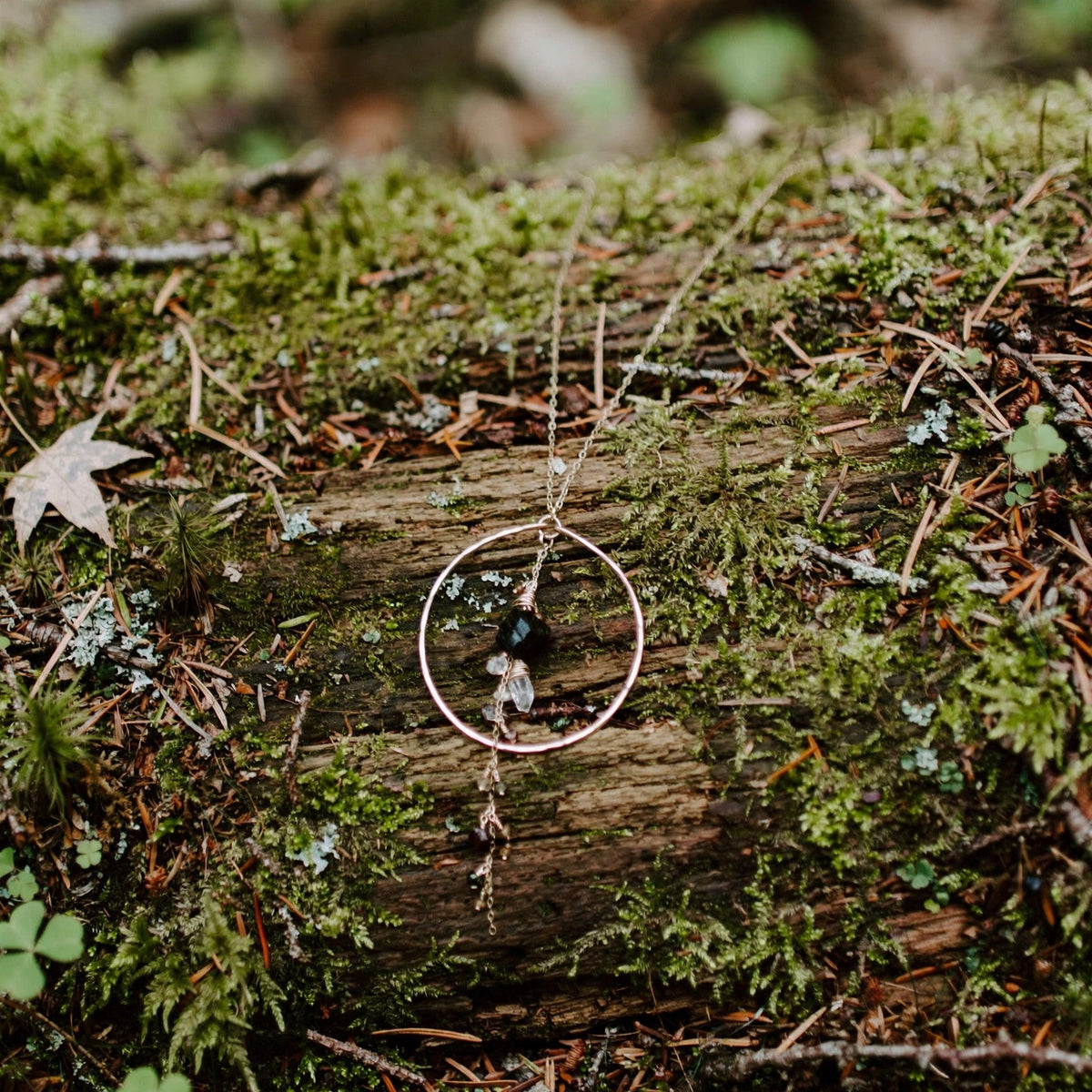 Enchanted Earth Hoop Necklace in 14k gold fill with a hammered hoop pendant, resting on a mossy downed log