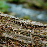 Equinox Herkimer Diamond Hoop Earrings in 14k gold fill with cascading herkimer diamond quartz dangles, resting on bark by a forest stream