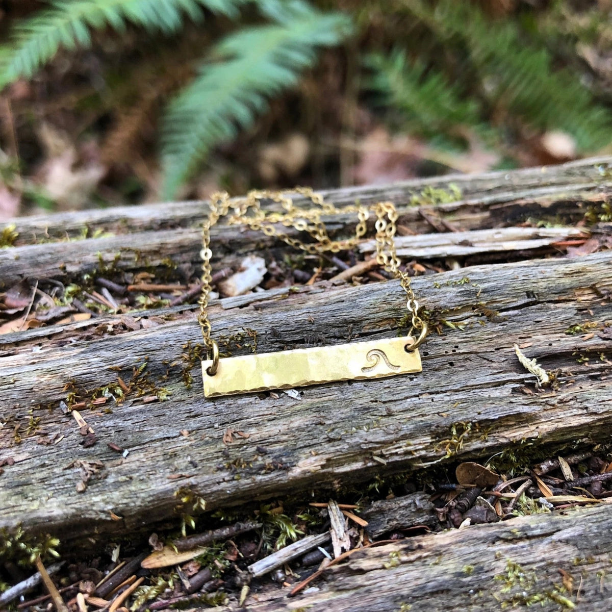 Hand Stamped Bar Necklace in 14k gold fill with a wave-stamped bar pendant, styled on driftwood