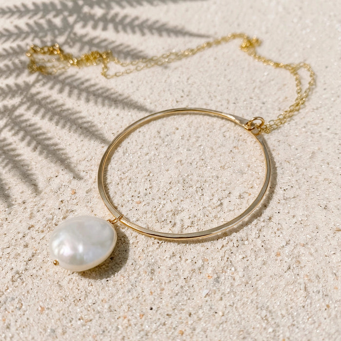 Pearl Hoop Drop Necklace in 14k gold fill, styled on pale sand at the beach