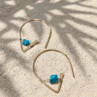 Kingman Turquoise Ear Threaders in 14k gold fill, styled on pale sand at the beach