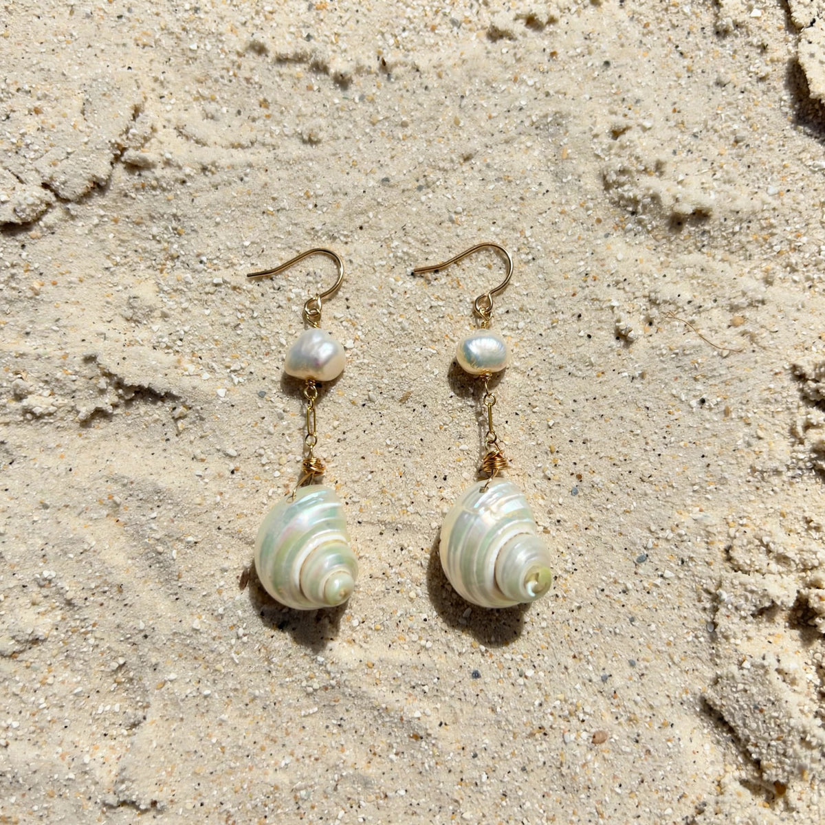 Moon and Tide Earrings in 14k gold fill, styled on pale sand at the beach