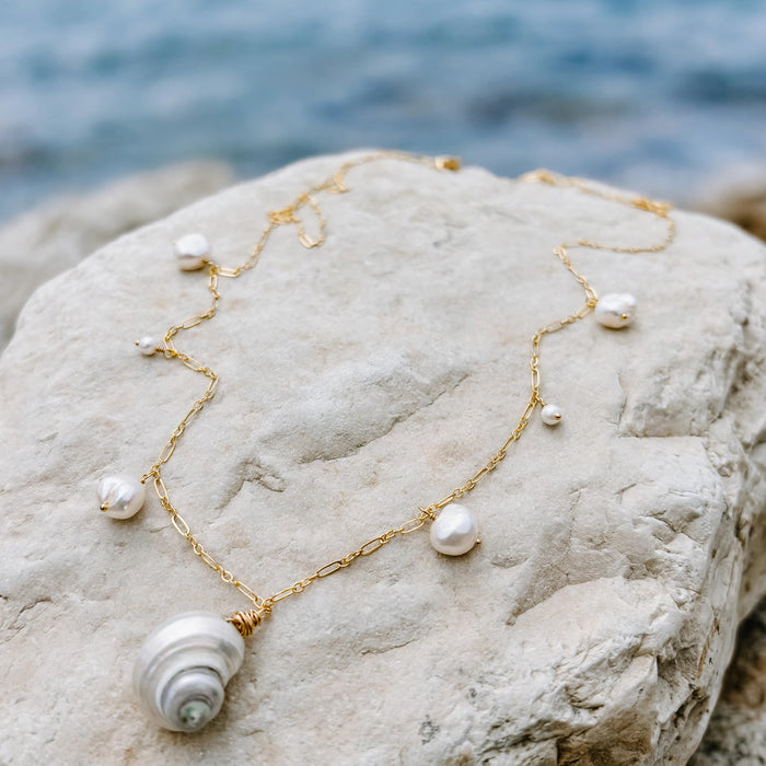 Moon and Tide Necklace in 14k gold fill, styled on pale sand at the beach