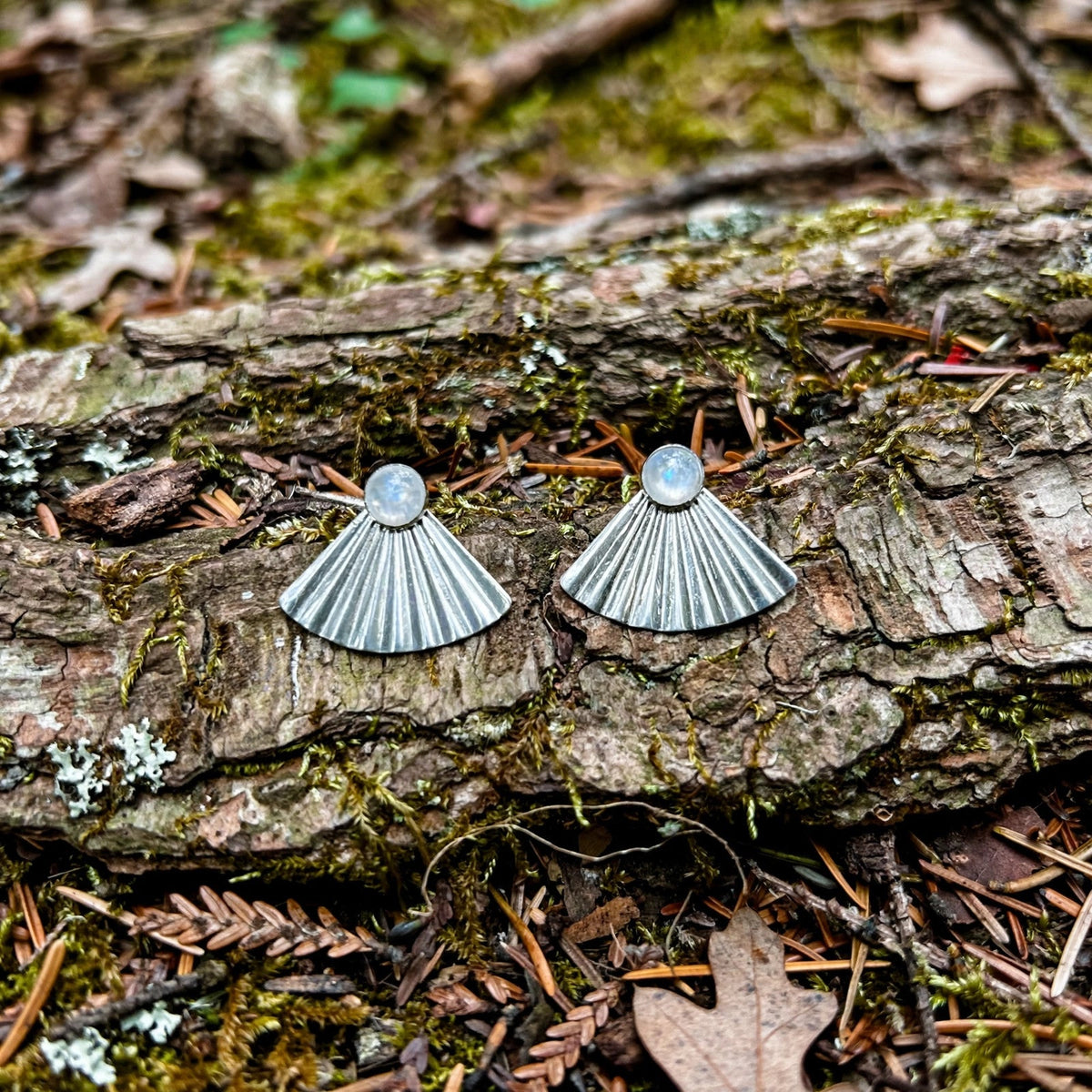 Moonrise Moonstone Ear Jacket Earrings in sterling silver with moonstone studs and fan ear jackets, resting on bark