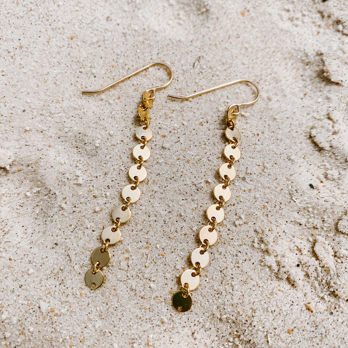 Sand Dollar Earrings in 14k gold fill, styled on pale sand at the beach