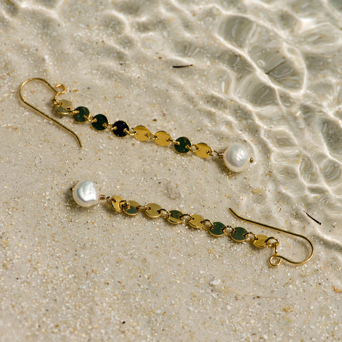 Sand Dollar Pearl Earrings in 14k gold fill, styled on pale sand at the beach