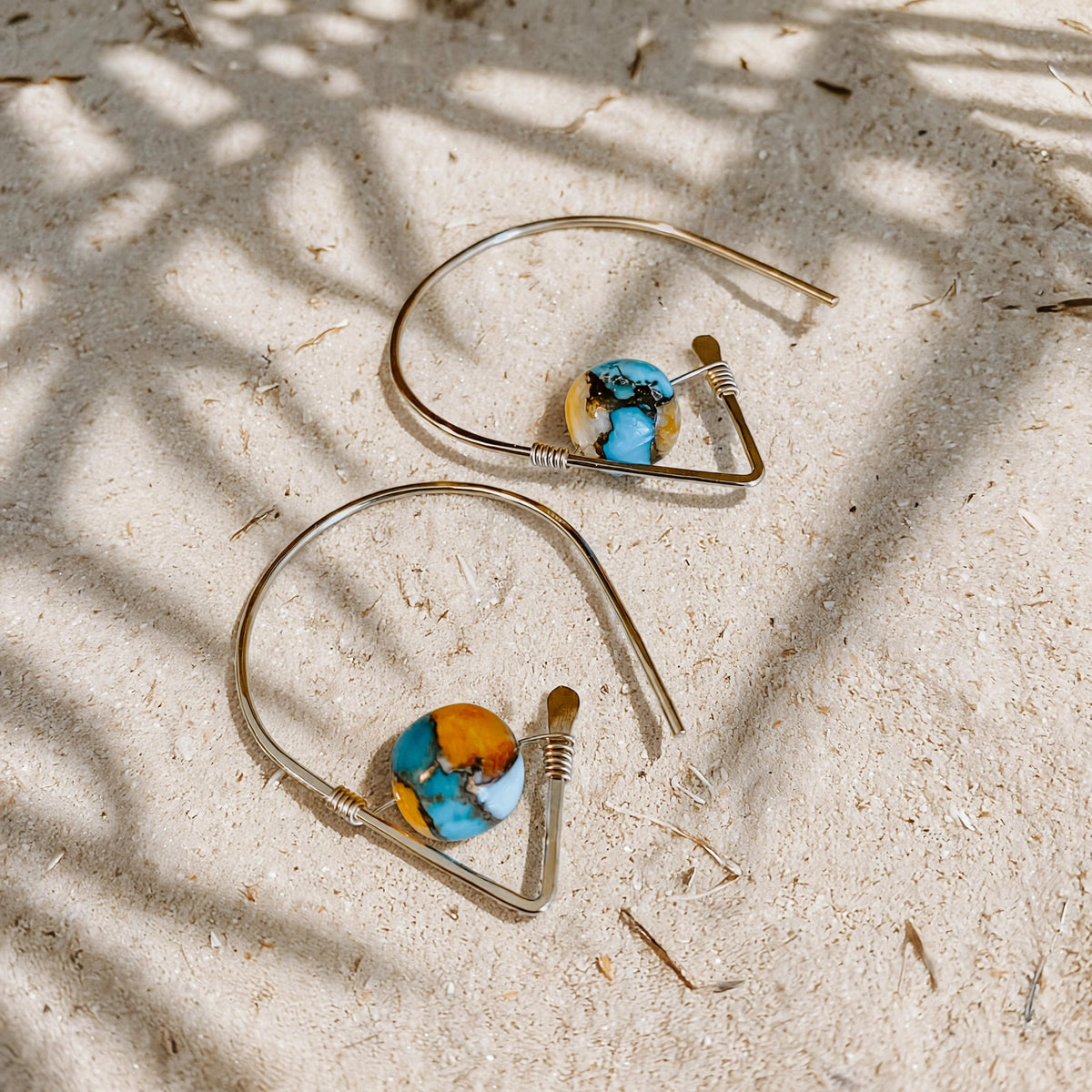 Spiny Oyster Turquoise Ear Threaders in 14k gold fill, styled on pale sand at the beach
