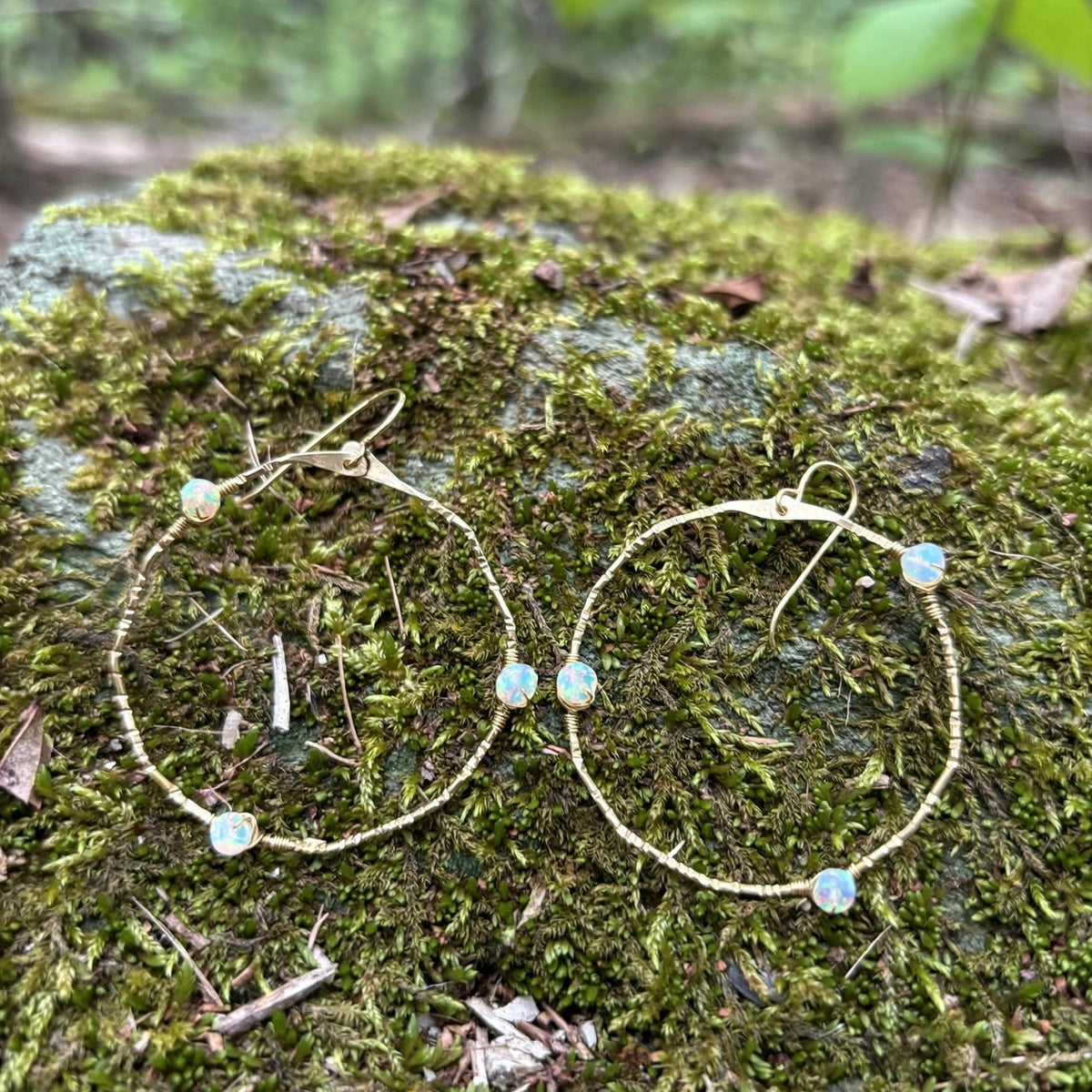 Stargazer Opal Hoop Earrings in 14k gold fill with opal beads on hammered hoops, styled on a mossy rock