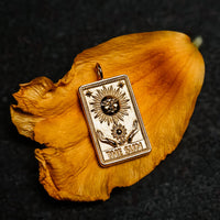 The sun tarot card pendant in solid 14k gold on a golden marigold petal