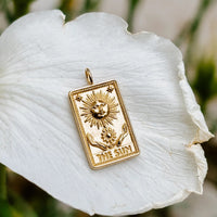 The sun tarot card pendant in solid 14k gold on a white petal, bright and airy