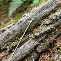 Wanderer's Stick Necklace in sterling silver with a hammered stick pendant and herkimer diamond, styled on driftwood